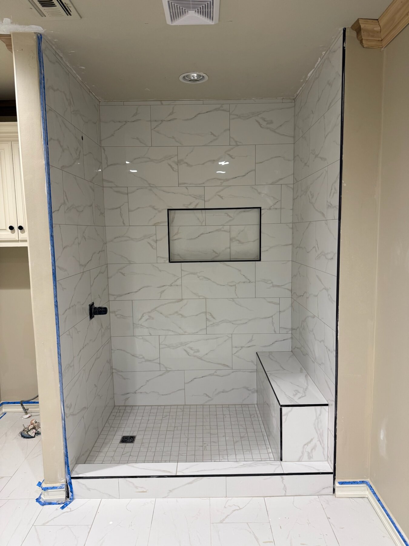 Custom marble tile shower with niche and bench installed by Reyna Tile & Flooring in Tulsa